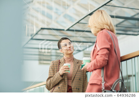 Two businesswomen drinking coffee 64936286