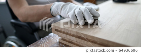 Man sits in a wheelchair and works as carpenter 64936696