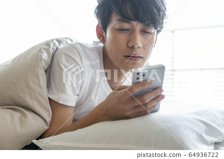 年輕人看著蒲團的智能手機 64936722