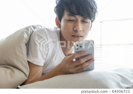 年輕人看著蒲團的智能手機 64936723