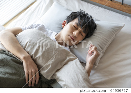 Young man sleeping in bed 64936727