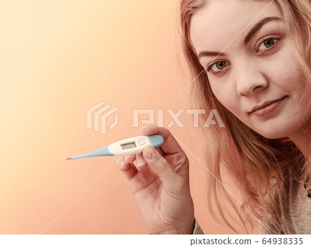 Sick ill woman with digital thermometer. 64938335