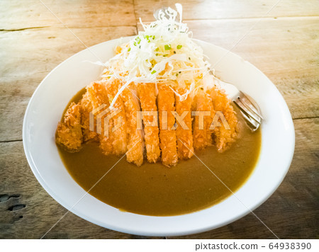 Pork fried in curry on Japanese rice and salad on a white plate on the table 64938390