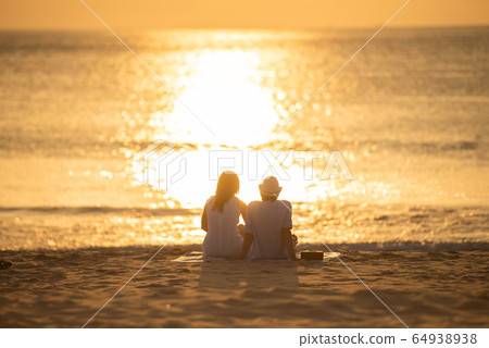 Couple in love watching sunset together on beach travel summer holidays.  64938938