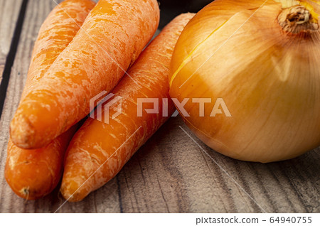 Juicy ripe onions and orange carrots on a wooden Juicy ripe onions and orange carrots on a wooden 64940755