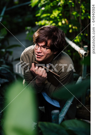Male scientist hiding in the thicket. Nature protection concept. 64940984