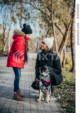 Happy mother and her daughter playing with dog in autumn park 64940985