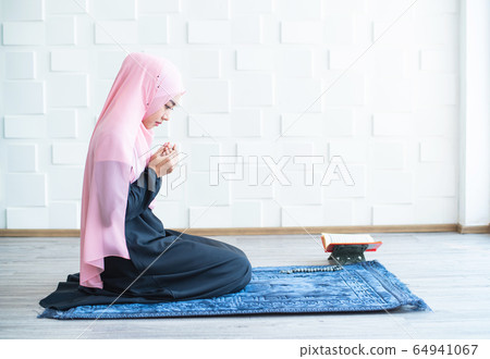 muslim woman pray on hijab praying on mat indoors 64941067