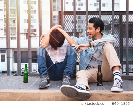 two men sit on street drink beer and cheerful. 64941805