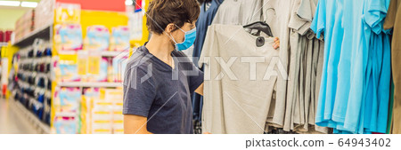 Man in a clothing store in a medical mask because of a coronovirus. Quarantine is over, now you can 64943402