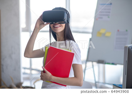 Dark-haired girl standing in the room wearing vr headset 64943908