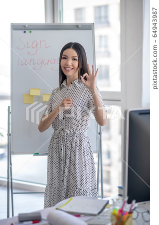 Young sign language interpreter standing near the flipchart 64943987