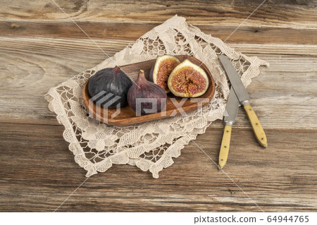 cut into half and whole ripe purple figs on table 64944765