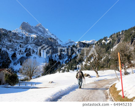 An old man walking on a snowy road in the Alps (Brownwald village, Switzerland) An old man walking on a snowy road in the Alps (Brownwald village, Switzerland) 64945233
