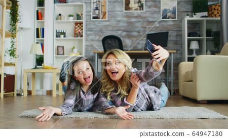 Mother and daughter lying on the floor 64947180