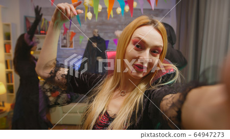 Pov of young woman dressed up like an enchantress invinting friends at halloween party Pov of young woman dressed up like an enchantress invinting friends at halloween party 64947273