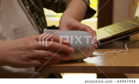 Female freelancer in kitchen turning on essential oil diffuser 64947494