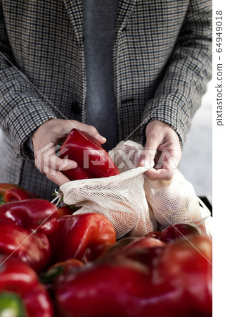 man using a reusable mesh bag at a greengrocer man using a reusable mesh bag at a greengrocer 64949018