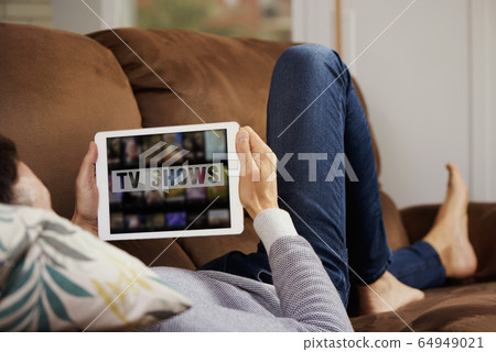 man and tablet with the text tv shows in it 64949021