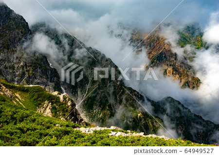 Happo ridge heading to Karamatsudake in the summer mountains of the Northern Alps. Futaki no Ryou seen between the clouds Happo ridge heading to Karamatsudake in the summer mountains of the Northern Alps. Futaki no Ryou seen between the clouds 64949527