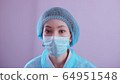 Asian doctor in a mask and a protective coat wearily looks at the camera. coronavirus epidemic 64951548