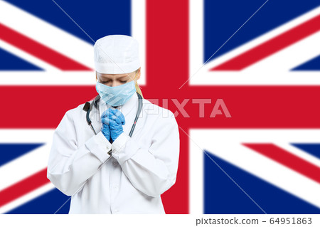 Female young doctor with stethoscope and face mask praying for God with United Kingdom national flag on background Female young doctor with stethoscope and face mask praying for God with United Kingdom national flag on background 64951863