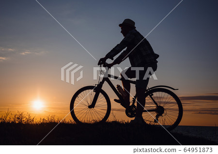 silhouette of a hipster man on a bicycle on sunset silhouette of a hipster man on a bicycle on sunset 64951873