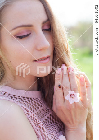 Ladybird and blonde woman in flowering garden Ladybird and blonde woman in flowering garden 64951902