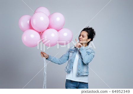girl in denim holding pastel pink air balloons girl in denim holding pastel pink air balloons 64952349