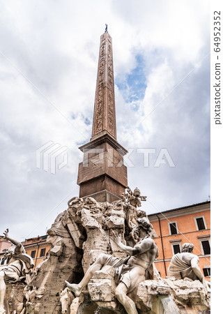 Four Rivers Fountain, Italian Fontana dei Quattro Fiumi, with obelisk and St Agnes Church on background. Piazza Navona square, Rome, Italy Four Rivers Fountain, Italian Fontana dei Quattro Fiumi, with obelisk and St Agnes Church on background. Piazza Navona square, Rome, Italy 64952352