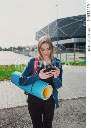 Toned young yoga instructor stand holding mat 64953439