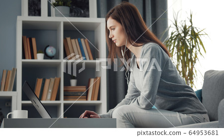 Woman using laptop sitting couch Woman using laptop sitting couch 64953681