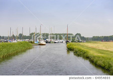 Little river at a harbour through the grasslands of Warmond. Little river at a harbour through the grasslands of Warmond. 64954693