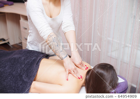 The master gives a back massage to the client. The master gives a back massage to the client. 64954909