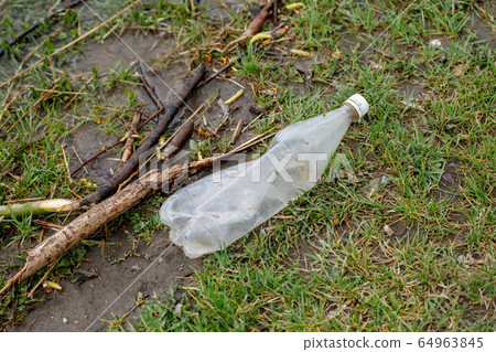 Waste bottle in grass, plastic garbage pollution 64963845
