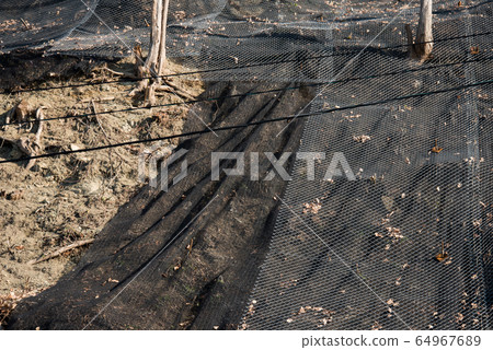 Strengthening the mountain slope with a metal mesh that prevents rockfall on the road. Abstract background of the security concept. Strengthening the mountain slope with a metal mesh that prevents rockfall on the road. Abstract background of the security concept. 64967689