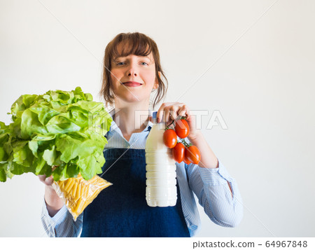 Woman in blue apron with food staples in hand Woman in blue apron with food staples in hand 64967848