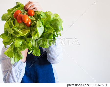 Woman in blue apron with fresh produce in hand Woman in blue apron with fresh produce in hand 64967851