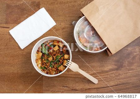 Takeaway asian food delivery. Stir fried pork and basil with rice in paper box on wooden background Takeaway asian food delivery. Stir fried pork and basil with rice in paper box on wooden background 64968817