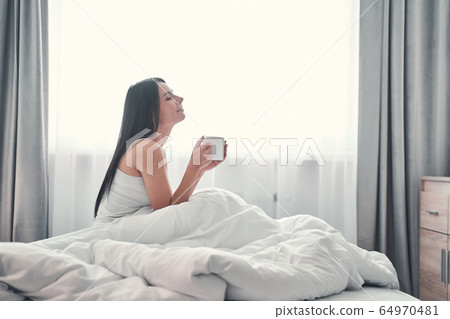 Young brunette woman enjoying cozy home morning 64970481