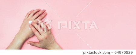 Woman moisturizing her hand with cosmetic cream with copy space on pink background in minimalism style. Woman moisturizing her hand with cosmetic cream with copy space on pink background in minimalism style. 64970829