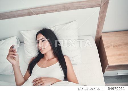 Attentive young woman staring at her thermometer 64970931