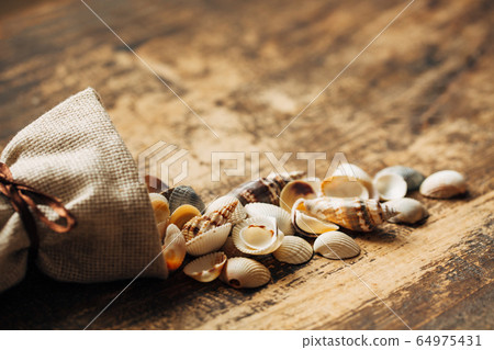 Small shells are poured out of a linen bag. Place 64975431