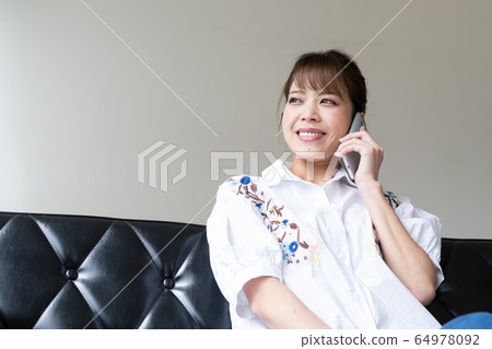 A woman enjoying a phone call slowly with a smartphone A woman enjoying a phone call slowly with a smartphone 64978092