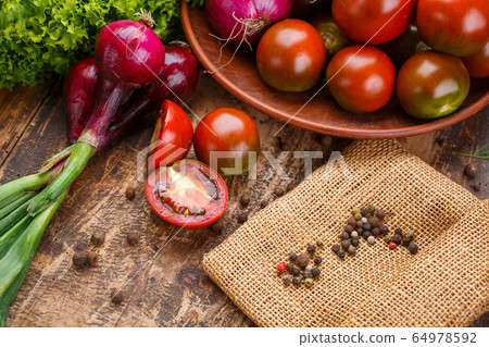 Tomatoes in a clay plate on a kitchen board. 64978592