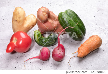 Pile of ripe ugly vegetables: potatoes, tomato, cucumbers, carrot and radishes on concrete background. Waste zero concept. Pile of ripe ugly vegetables: potatoes, tomato, cucumbers, carrot and radishes on concrete background. Waste zero concept. 64978863