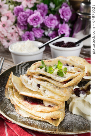 Crepes with ricotta cheese and blackcurrant jam. 64979525