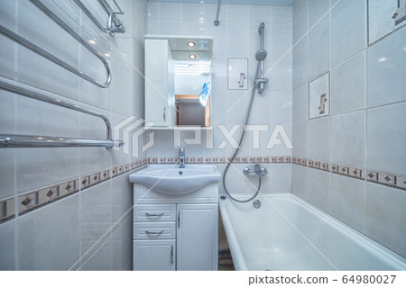 Small white tile bathroom with bath tube Small white tile bathroom with bath tube 64980027