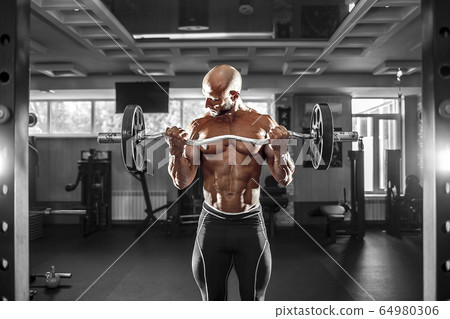 Muscular man working out in gym doing exercises with dumbbells at biceps, strong male naked torso abs Muscular man working out in gym doing exercises with dumbbells at biceps, strong male naked torso abs 64980306
