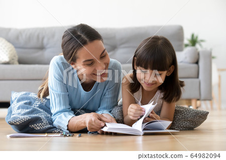 Caring mother reading book with little kid girl at home 64982094
